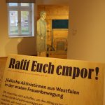 Ausstellungsansicht mit Texttafel und Figur einer Frau